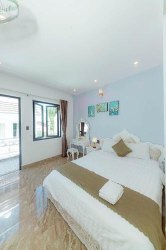 a white bedroom with a large bed and a desk at Sunrise Valley Dalat Hotel in Da Lat