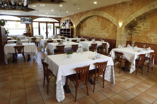 バルデロブレスにあるHotel El Saltのテーブルと椅子(白いテーブルクロス付)が備わるレストラン