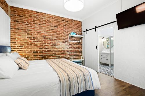 a bedroom with a bed and a brick wall at Surfaris in Crescent Head