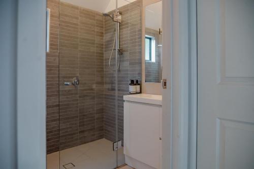 a bathroom with a shower with a sink and a mirror at Candlebark at Boardwalk Villas in Metung