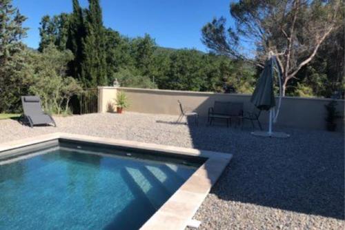 - une piscine et un parasol dans la cour dans l'établissement Maison au pied du lubéron, à Lauris