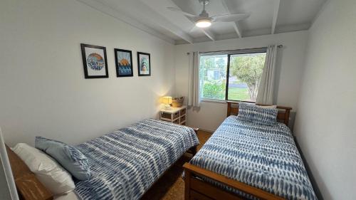 Un dormitorio con dos camas y una ventana. en Drift at Rainbow 4 Bedroom, en Rainbow Beach
