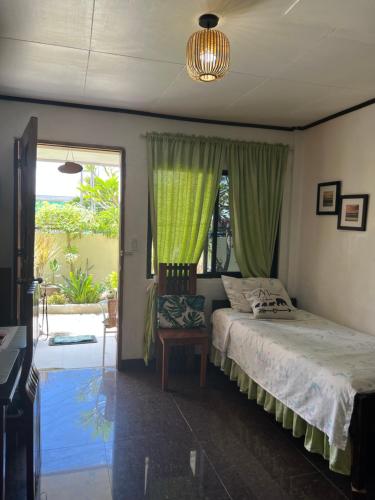 Panagsama Holiday Cottage في موالبوال: غرفة نوم بسرير ونافذة مع ستائر خضراء