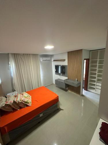 a bedroom with an orange bed and a television at Casa de Temporada Camaçari in Barra de Jacuípe