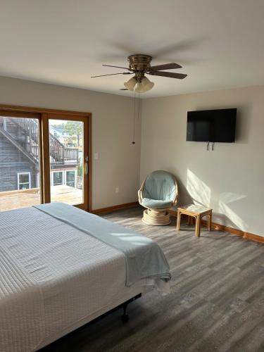 a bedroom with a bed and a fan and a chair at Canal Front Boater's Paradise in Kill Devil Hills