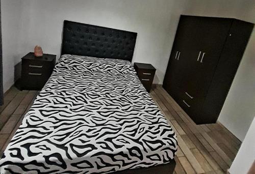 a bedroom with a bed with a black and white comforter at Complejo Lua in Villa Cura Brochero