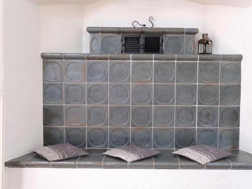 a tile fireplace with two pillows on a shelf at Holiday home Mühle Catharina in Oldenswort