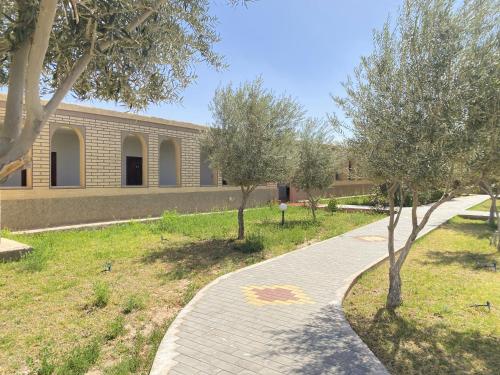 a brick walkway in front of a building with trees at IGHIZ INN resort in Er Rachidia