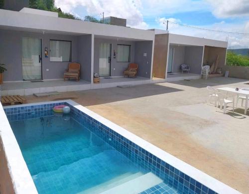 a house with a swimming pool in front of it at Vila Negreiros Serra Negra Casa 3 in Bezerros