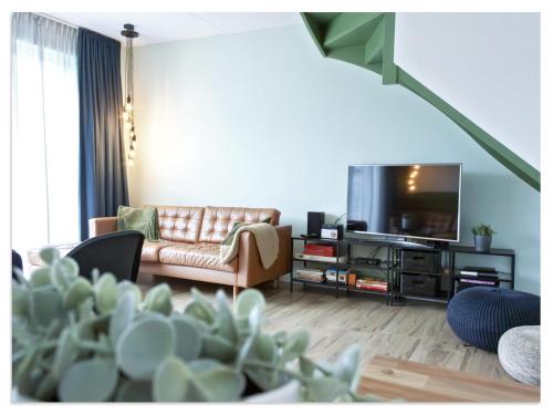 a living room with a couch and a flat screen tv at Waterfront Holiday Home with Terrace Views in Stavoren