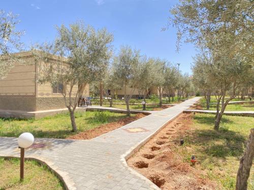 a walkway in a park with trees and a building at IGHIZ INN resort in Er Rachidia