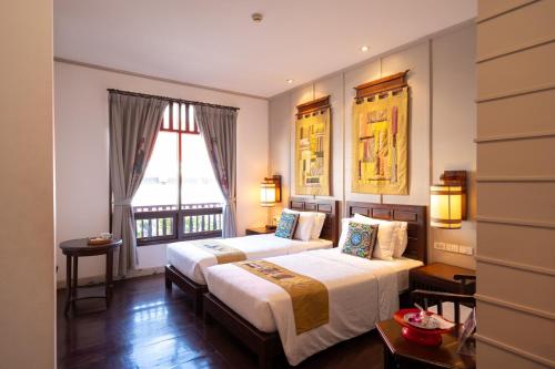 a hotel room with two beds and a window at Pukha Nanfa Hotel in Nan