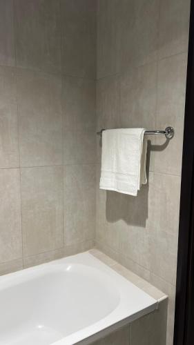 a bathroom with a tub and a white towel at Trendy Stay Apartments in Muscat