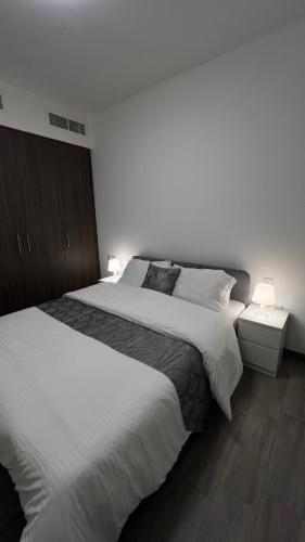 a bedroom with a large white bed and two lamps at Trendy Stay Apartments in Muscat
