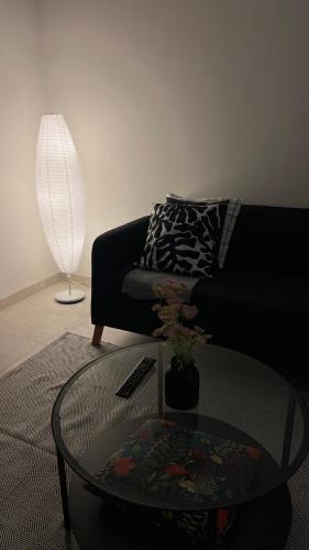 a living room with a black couch and a glass table at Trendy Stay Apartments in Muscat