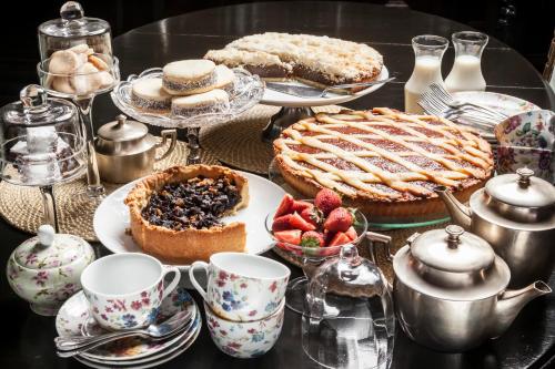 a table topped with desserts and tea cups and a pie at La Alondra, Casa de huéspedes in Corrientes