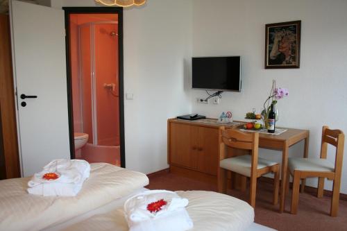 a hotel room with two beds and a desk and a television at Hotel Gasthof Schweizerhaus in Stuhlfelden