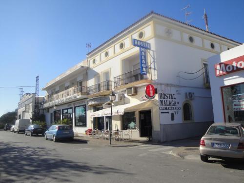 a large white building with cars parked in front of it at Hostal Málaga in Arcos de la Frontera