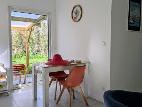 - une table avec deux chaises et un chapeau rouge dans l'établissement Charmant gîte Coquelicot près des plages vendéennes - FR-1-426-573, à Saint-Gervais