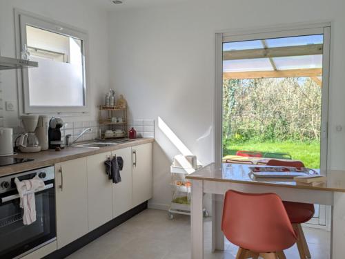 une cuisine avec un comptoir et une chaise rouge dans l'établissement Charmant gîte Coquelicot près des plages vendéennes - FR-1-426-573, à Saint-Gervais