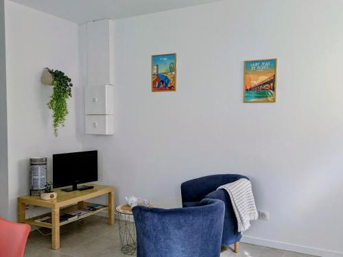 un salon avec deux chaises bleues et une télévision dans l'établissement Charmant gîte Coquelicot près des plages vendéennes - FR-1-426-573, à Saint-Gervais