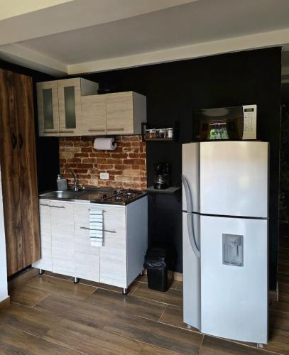 a kitchen with a white refrigerator and a brick wall at Confortable Apartamento a 20 mt del Parque Principal in Salento