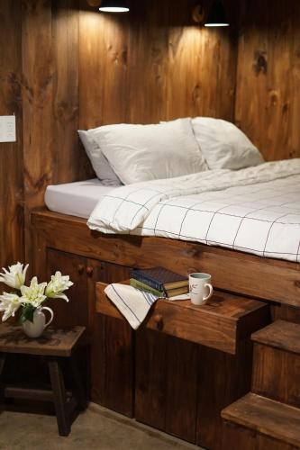 a bed with white sheets and two cups on a table at Maison De Oliu in Ấp Thiện Lập