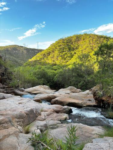 a river with rocks and a hill in the background at Viver de Temporada Canindé- 15 Minutos de Piranhas in Canindé de São Francisco