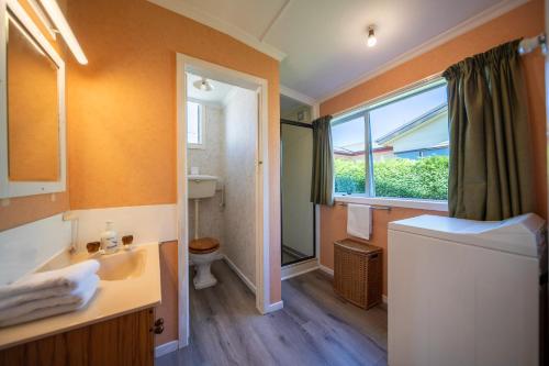 a bathroom with a sink and a toilet and a window at Mountain Serenity - Te Anau Holiday Home in Te Anau