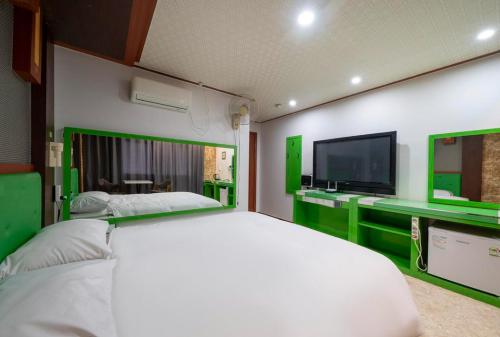 a bedroom with a white bed and a flat screen tv at Jjak motel in Incheon