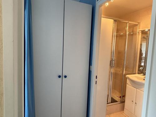 La salle de bains est pourvue d'un placard blanc et d'un lavabo. dans l'établissement Charmant 2 pièces avec loggia à deux pas de la plage, parking, tout équipé - FR-1-712-38, à Villers-sur-Mer