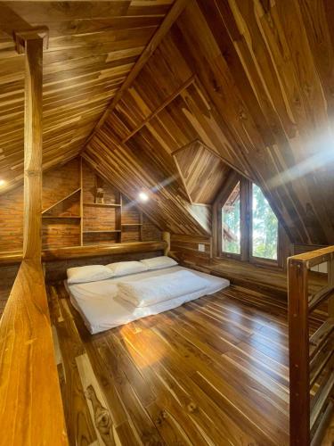 a bed in the middle of a wooden cabin at KND Wind Valley Bình Thuận in Xóm Chum Găng
