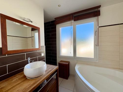 ein Badezimmer mit Waschbecken, Badewanne und Fenster in der Unterkunft Spacieuse Maison avec Piscine Privée - Cœur de Saint Jean de Monts - FR-1-323-381 in Saint-Jean-de-Monts