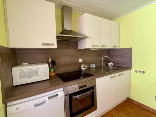 une cuisine avec des armoires blanches et un micro-ondes dans l'établissement Maison à Saint-Hilaire-de-Riez à proximité de la plage, 3 chambres, terrasse - FR-1-323-564, à Saint-Hilaire-de-Riez