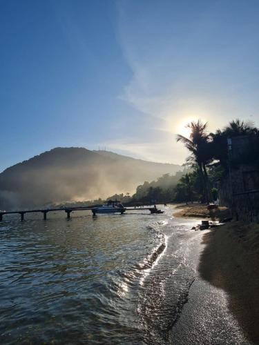 a view of a river with a bridge and a palm tree at Suíte 1 - Vila dos Pescadores in Angra dos Reis