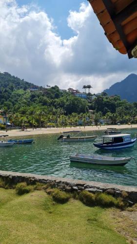 three boats in the water near a beach at Suíte 1 - Vila dos Pescadores in Angra dos Reis