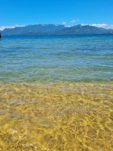 a clear body of water with mountains in the background at Suíte 1 - Vila dos Pescadores in Angra dos Reis