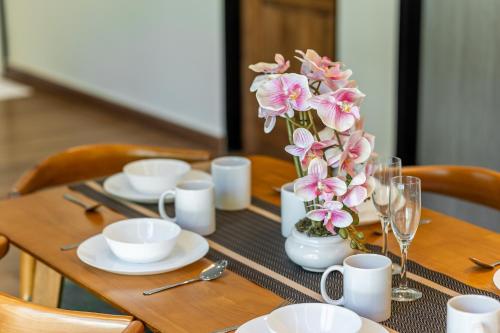 a wooden table with a vase of flowers on it at La Ferringhi Villa - Tropical Collection, by ALV in Batu Ferringhi