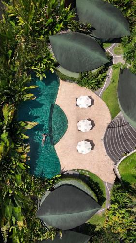 an aerial view of a swimming pool with umbrellas at De Moksha Eco Friendly Boutique Resort in Tabanan