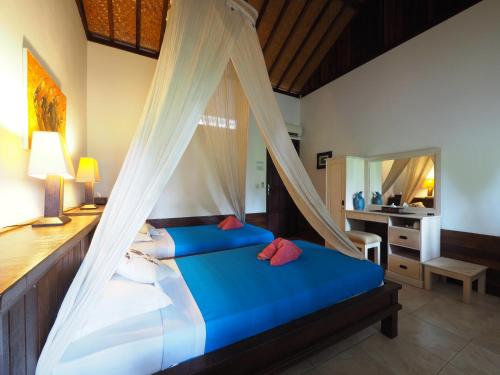 a bedroom with a bed with a mosquito net at Reef Seen Divers' Resort in Pemuteran
