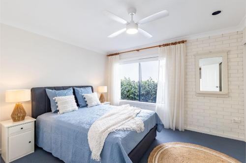 una camera da letto con un letto blu e una finestra di Maestral II - short stroll to stunning beach a Boat Harbour