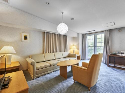 a living room with a couch and a table at Hakuba Alps Hotel in Otari