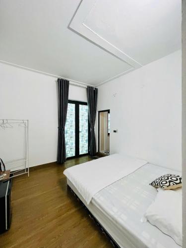 a white bedroom with a large bed and windows at Tram Homestay - Venuestay in Tam Ðảo