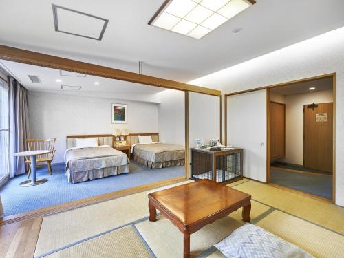 a hotel room with two beds and a table at Hakuba Alps Hotel in Otari