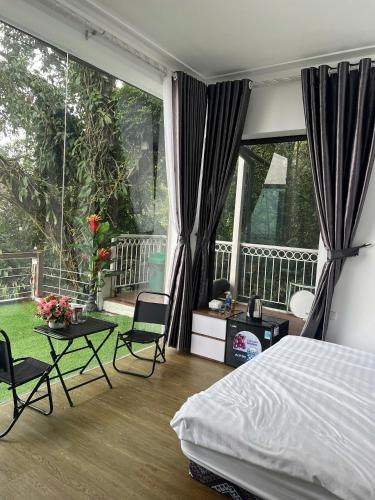 a bedroom with a bed and a balcony with windows at Tram Homestay - Venuestay in Tam Ðảo