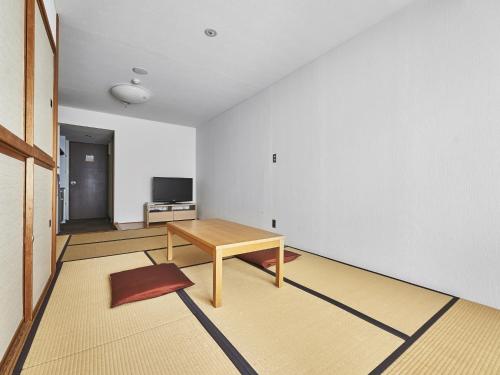 a living room with a table and a television at Hakuba Alps Hotel in Otari