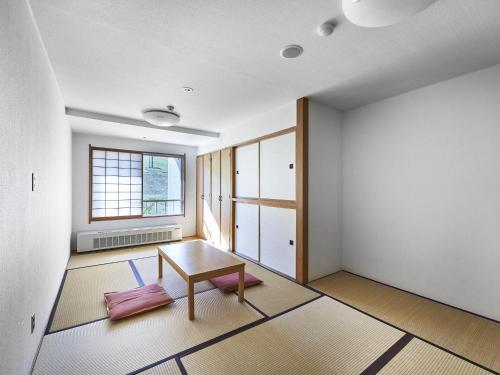 a living room with a table and a window at Hakuba Alps Hotel in Otari