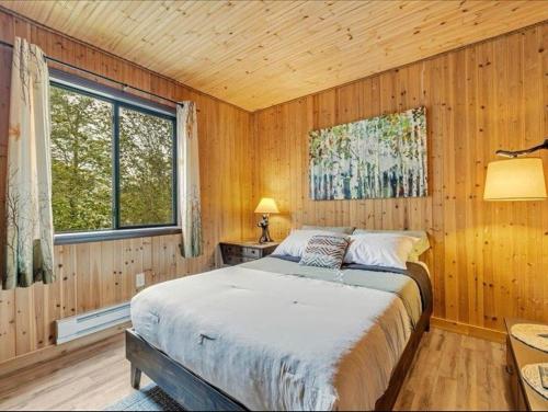 Pocono Country PlaceにあるCabin Retreat with Hot Tubの木製の部屋にベッド1台が備わるベッドルーム1室があります。