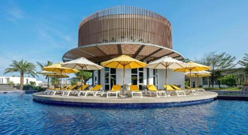 a pool with chairs and umbrellas in front of a building at Oceanami Villas Resort Beach in Long Hai