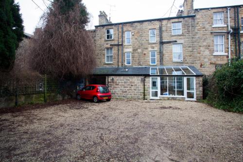 a red car parked in front of a brick building at The Camberley in Harrogate
